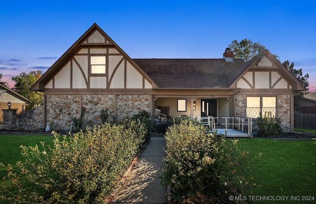 tudor house with a porch and a yard