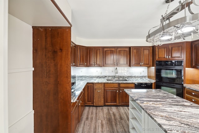 kitchen with dark wood-type flooring, backsplash, sink, light stone countertops, and black appliances