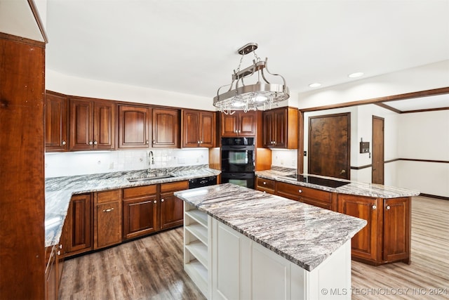 kitchen featuring wood-type flooring, black appliances, sink, a kitchen island, and pendant lighting