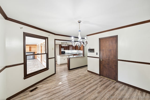 kitchen featuring light hardwood / wood-style flooring, crown molding, pendant lighting, a notable chandelier, and sink