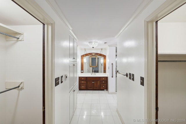 corridor with sink, ornamental molding, and light tile patterned floors