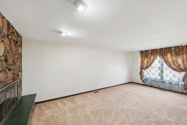 interior space with ornamental molding, light colored carpet, and a fireplace