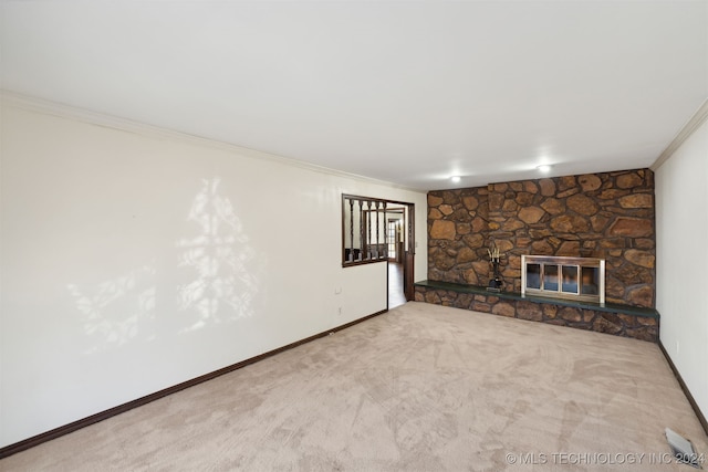 unfurnished living room featuring a stone fireplace, crown molding, and carpet flooring