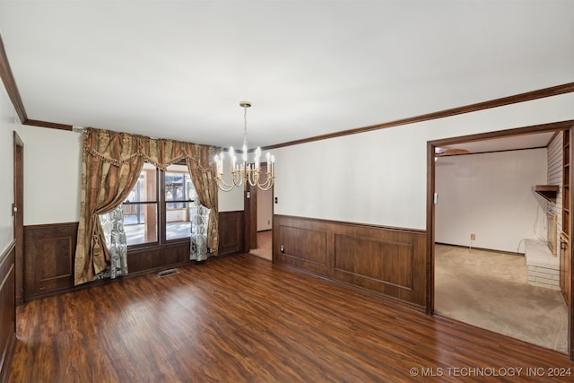 unfurnished dining area featuring ornamental molding, an inviting chandelier, and dark hardwood / wood-style floors