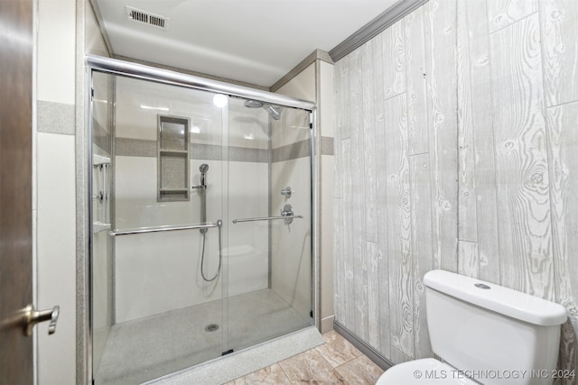 bathroom featuring toilet, wood walls, and a shower with door