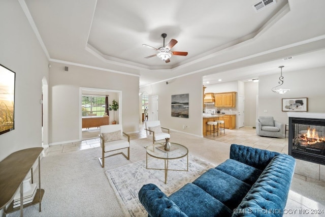 living room with crown molding, ceiling fan, and a raised ceiling