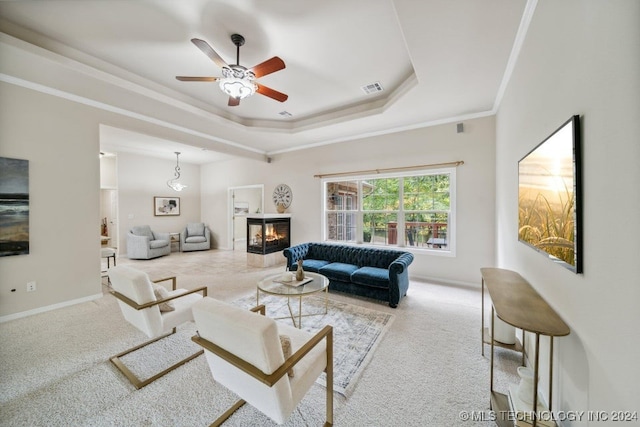 living room with crown molding, a raised ceiling, light carpet, and ceiling fan