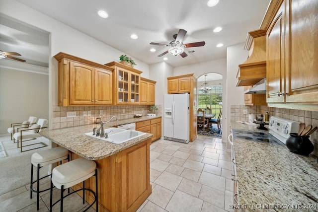 kitchen with white appliances, sink, decorative backsplash, a breakfast bar, and ventilation hood