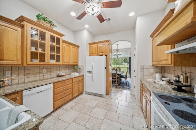 kitchen with decorative backsplash, light tile patterned floors, light stone countertops, ceiling fan with notable chandelier, and white appliances