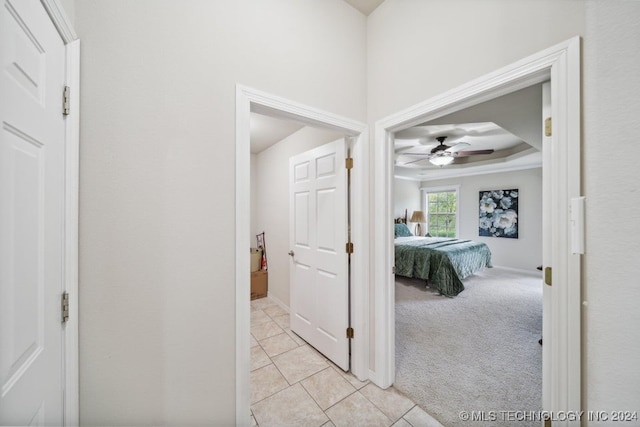 corridor featuring light colored carpet and a raised ceiling