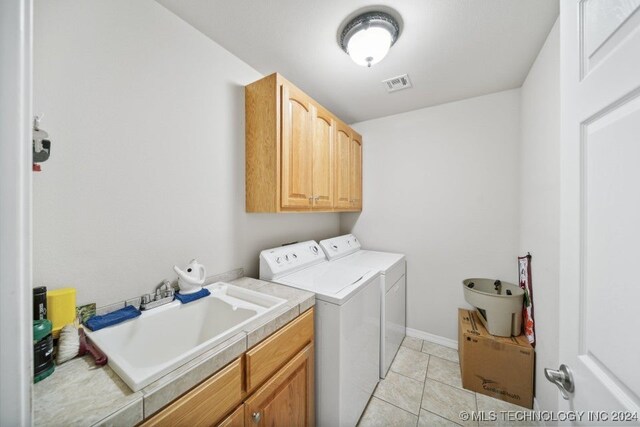 clothes washing area featuring cabinets, sink, washing machine and clothes dryer, and light tile patterned floors