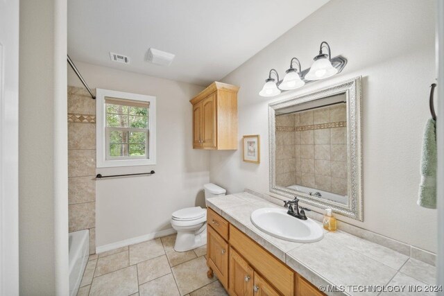 full bathroom with toilet, tiled shower / bath, vanity, and tile patterned floors