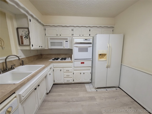 kitchen featuring white cabinetry, a textured ceiling, light hardwood / wood-style flooring, sink, and white appliances