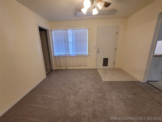 empty room featuring ceiling fan, a textured ceiling, and light colored carpet