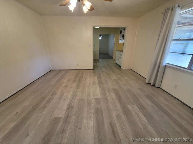 empty room featuring light hardwood / wood-style flooring, a textured ceiling, and ceiling fan