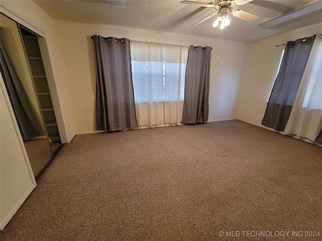 carpeted spare room with a textured ceiling and ceiling fan