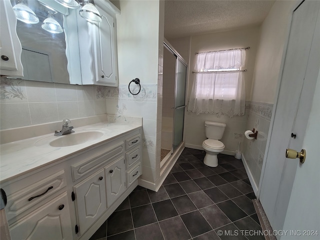 bathroom with toilet, a textured ceiling, vanity, and tile walls