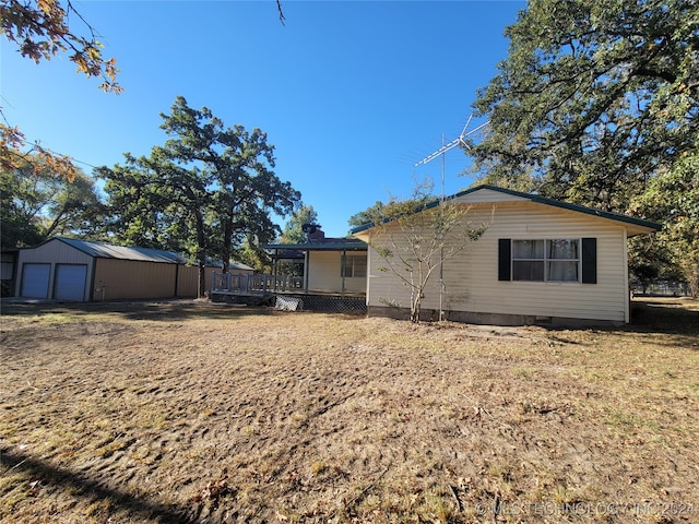 exterior space with a garage, a deck, and an outbuilding