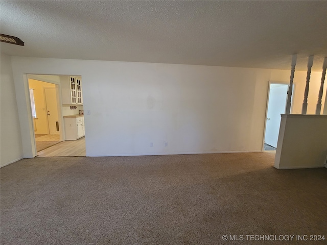 unfurnished living room featuring a textured ceiling and light colored carpet