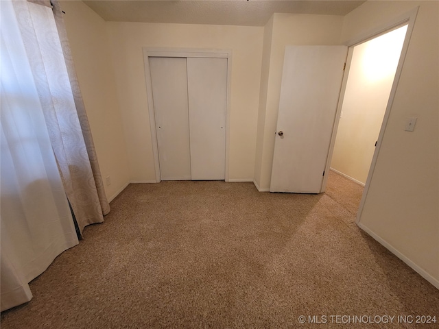 unfurnished bedroom with light carpet and a closet