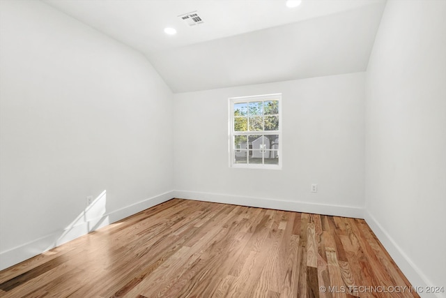 spare room with wood-type flooring and lofted ceiling