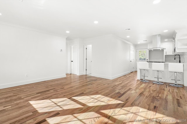 unfurnished living room with light hardwood / wood-style flooring and crown molding