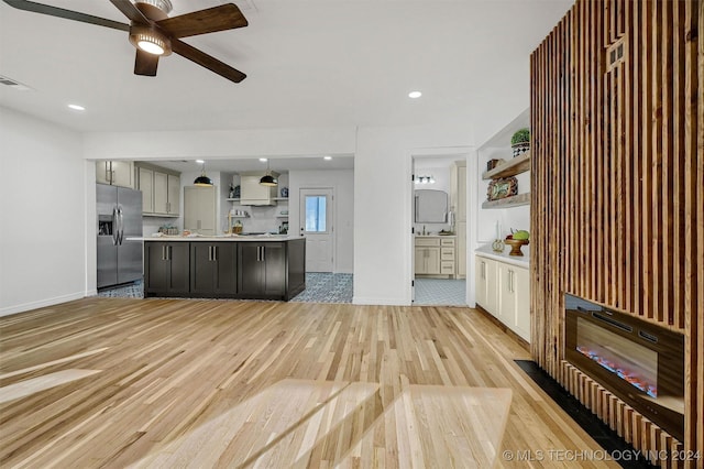 kitchen featuring pendant lighting, stainless steel fridge, ceiling fan, a kitchen island, and light wood-type flooring