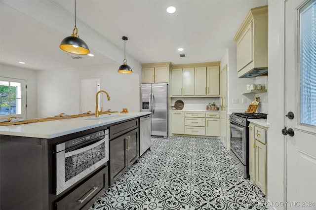 kitchen featuring stainless steel appliances, hanging light fixtures, sink, and cream cabinetry