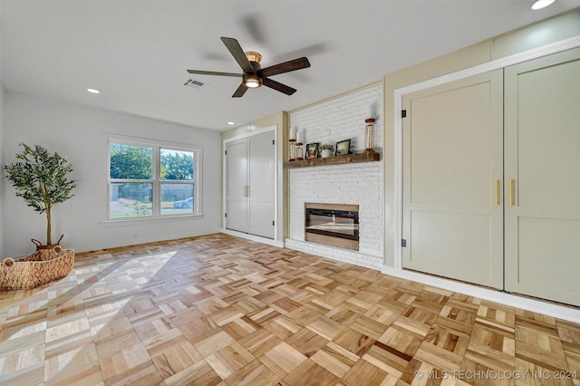 unfurnished living room featuring ceiling fan, light parquet flooring, and a fireplace