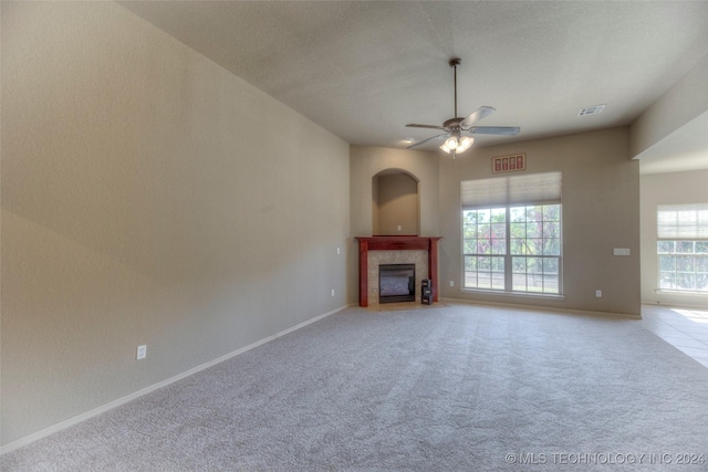 unfurnished living room featuring plenty of natural light, light colored carpet, a tile fireplace, and ceiling fan