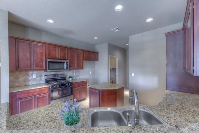 kitchen featuring light stone counters, sink, decorative backsplash, and stainless steel appliances