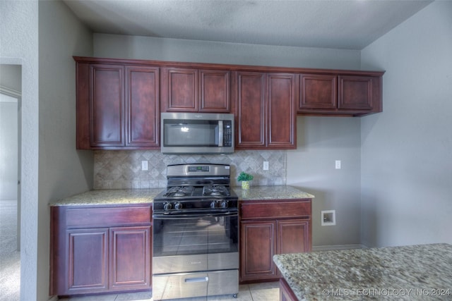 kitchen with tasteful backsplash, appliances with stainless steel finishes, and light stone counters