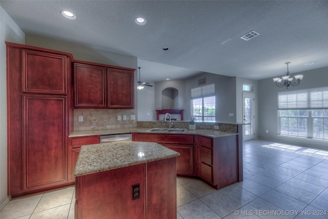 kitchen with a kitchen island, tasteful backsplash, sink, stainless steel dishwasher, and light stone counters