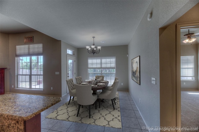 tiled dining space with ceiling fan with notable chandelier and a textured ceiling