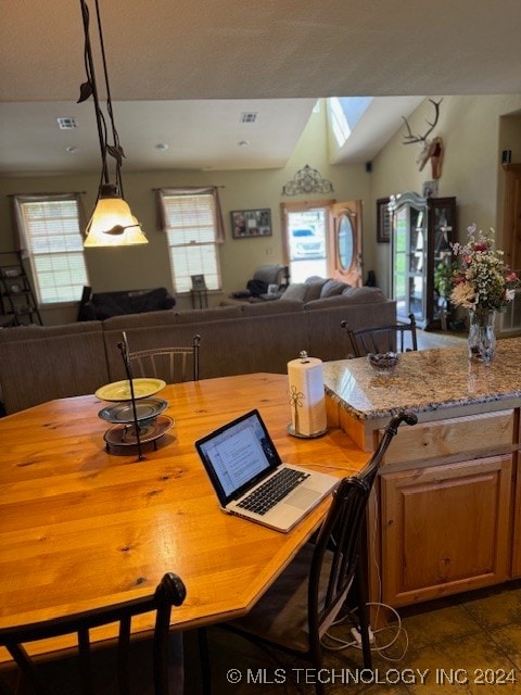 dining space with a skylight and dark tile patterned flooring