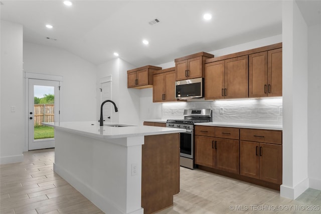 10804 S 274th Ave E, Coweta, OK 74429 - kitchen featuring appliances with stainless steel finishes, a sink, lofted ceiling, an island with sink, and brown cabinets