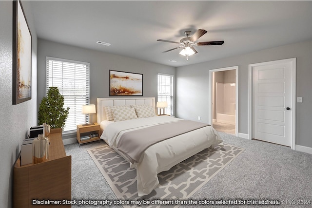 bedroom with light carpet, multiple windows, connected bathroom, and ceiling fan