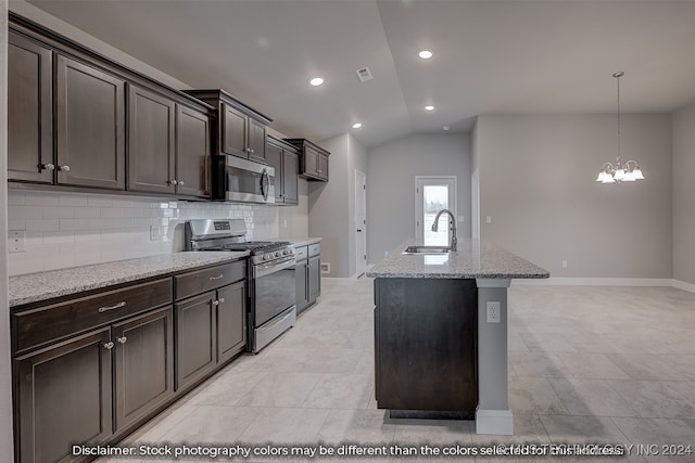 kitchen with a center island with sink, appliances with stainless steel finishes, light stone countertops, vaulted ceiling, and sink