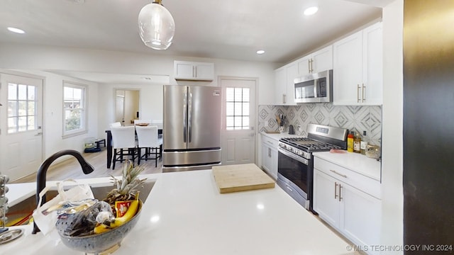 kitchen with white cabinetry, stainless steel appliances, pendant lighting, and plenty of natural light