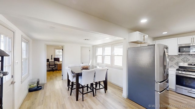 kitchen featuring light hardwood / wood-style flooring, white cabinetry, tasteful backsplash, and stainless steel appliances