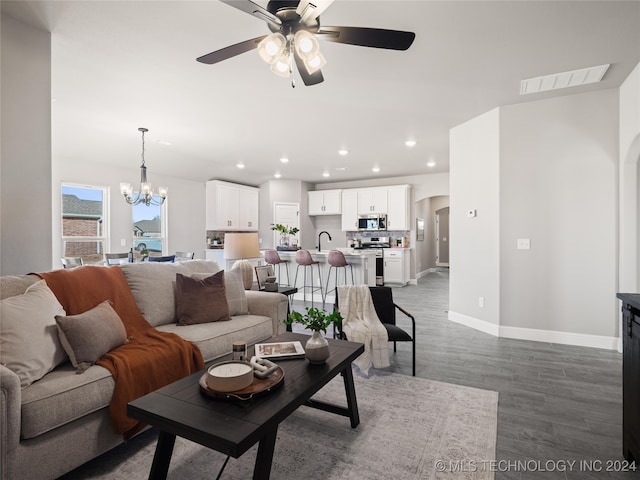 living room featuring ceiling fan with notable chandelier and dark hardwood / wood-style flooring