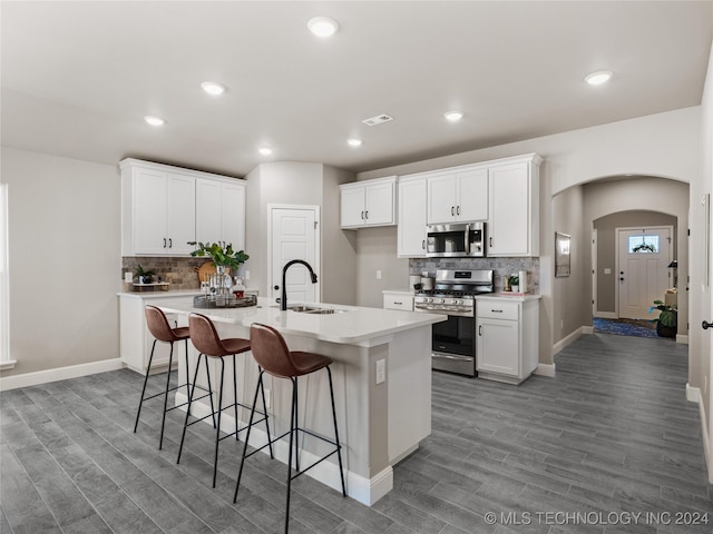 kitchen featuring a kitchen island with sink, stainless steel appliances, sink, light wood-type flooring, and white cabinetry