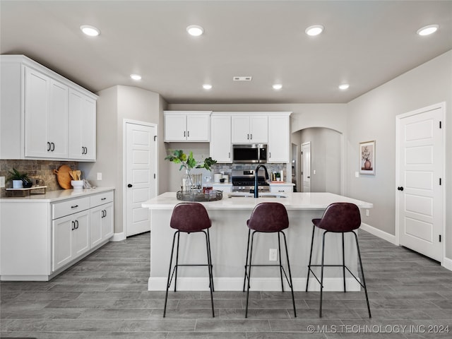 kitchen with white cabinetry, stainless steel appliances, sink, and a kitchen island with sink