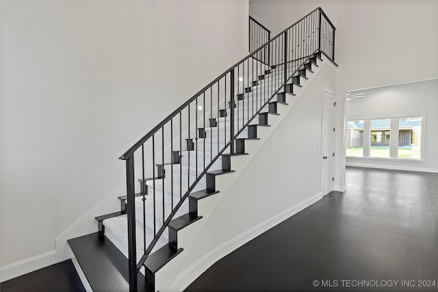 stairway with hardwood / wood-style floors and a high ceiling