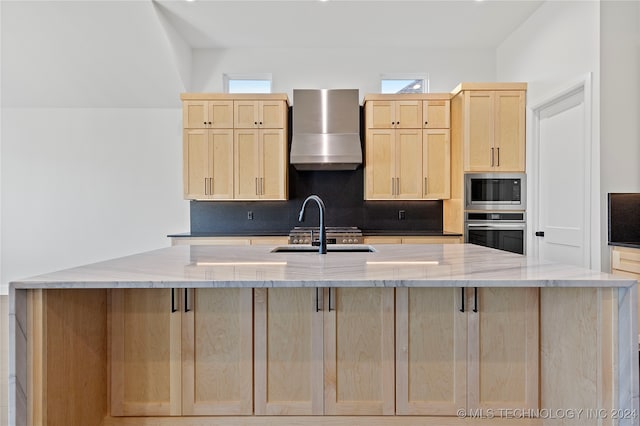 kitchen featuring light stone counters, stainless steel appliances, sink, wall chimney range hood, and light brown cabinets