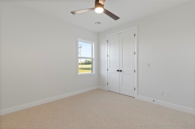 unfurnished bedroom with ceiling fan, a closet, and light carpet