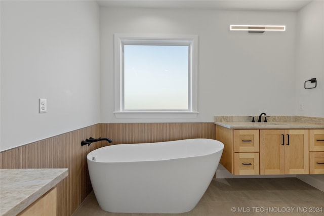 bathroom featuring tile patterned floors, a bathing tub, wooden walls, and vanity