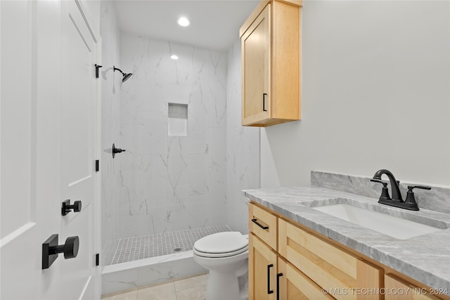 bathroom with a tile shower, vanity, and toilet