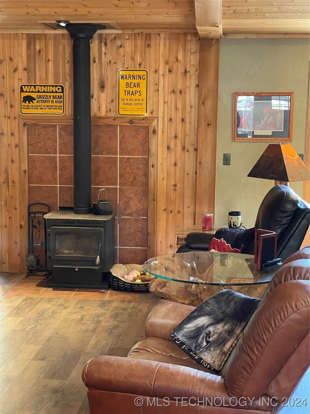 living room featuring wooden walls, wood-type flooring, a wood stove, and wooden ceiling