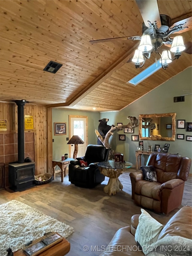 living room featuring lofted ceiling with skylight, hardwood / wood-style floors, wood ceiling, and a wood stove